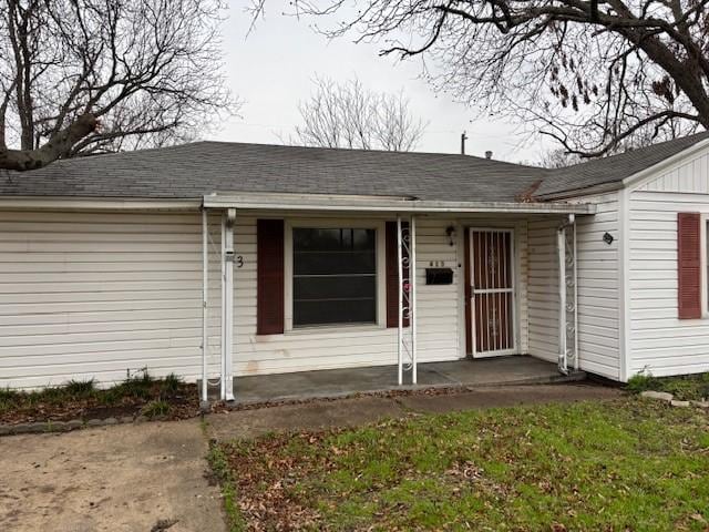 entrance to property featuring roof with shingles and a lawn