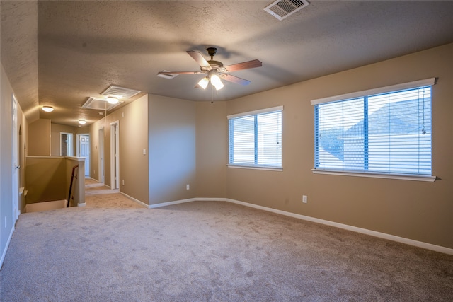 empty room with light carpet, a textured ceiling, visible vents, and attic access