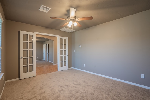 empty room featuring arched walkways, french doors, light colored carpet, visible vents, and baseboards