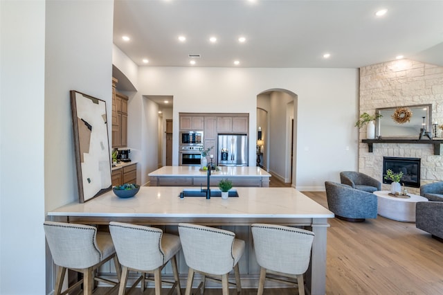 2521 Warwick Dr, Celina, TX 75009 - kitchen with light wood finished floors, stainless steel appliances, a center island, arched walkways, and a breakfast bar