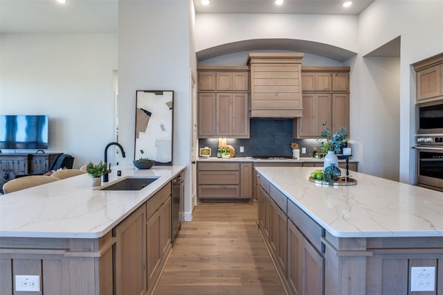 kitchen with a center island, light wood finished floors, tasteful backsplash, appliances with stainless steel finishes, and a sink