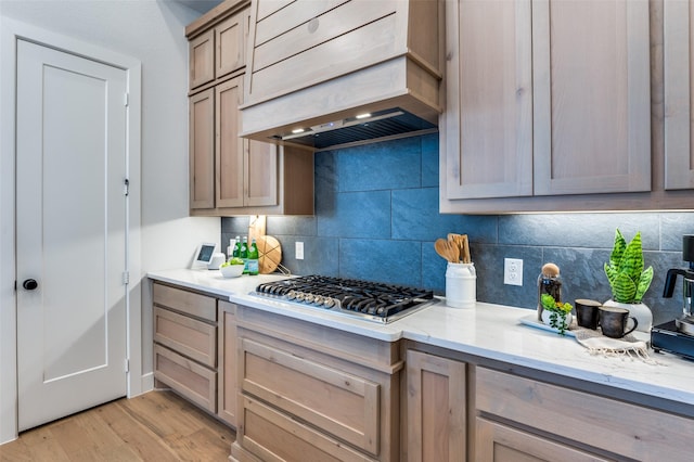 2521 Warwick Dr, Celina, TX 75009 - kitchen featuring light stone counters, stainless steel gas cooktop, light wood-type flooring, premium range hood, and backsplash