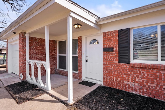 property entrance with a garage and brick siding