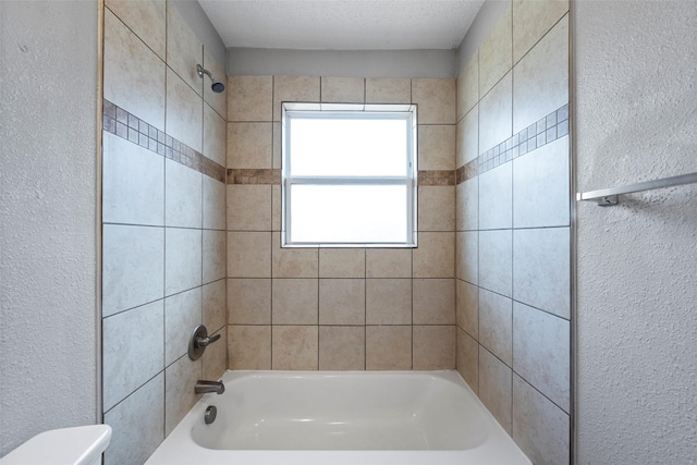 bathroom featuring a textured ceiling, a textured wall, shower / washtub combination, and toilet