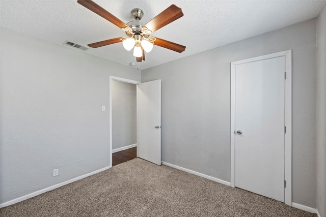 unfurnished bedroom with baseboards, visible vents, a ceiling fan, carpet, and a textured ceiling