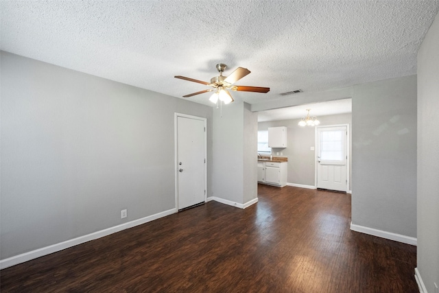 unfurnished room featuring visible vents, baseboards, dark wood finished floors, a textured ceiling, and ceiling fan with notable chandelier