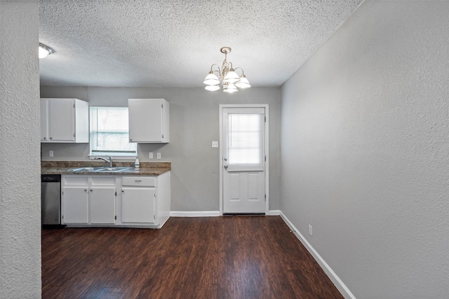 kitchen with dishwasher, dark countertops, hanging light fixtures, white cabinetry, and a sink