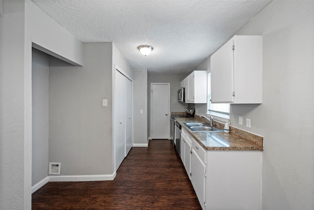 kitchen featuring dark wood finished floors, appliances with stainless steel finishes, white cabinetry, a sink, and baseboards