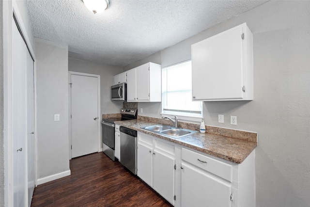 kitchen with a textured ceiling, dark wood-type flooring, a sink, white cabinets, and appliances with stainless steel finishes