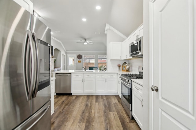 kitchen featuring stainless steel appliances, crown molding, a sink, and a peninsula