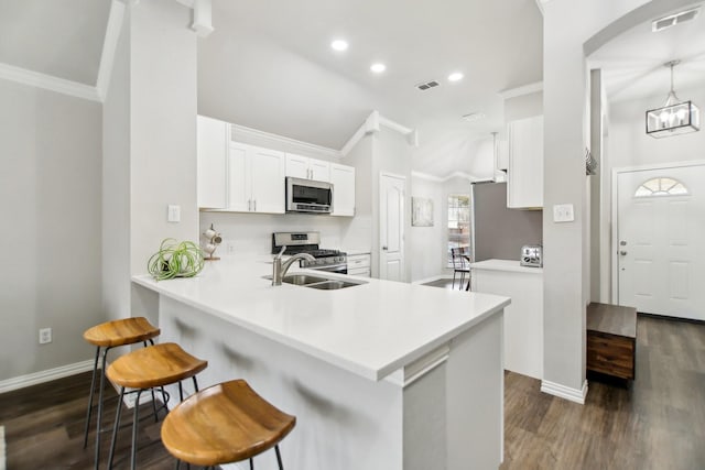 kitchen featuring visible vents, appliances with stainless steel finishes, dark wood-type flooring, white cabinetry, and a kitchen breakfast bar