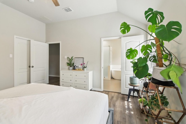 bedroom featuring baseboards, visible vents, lofted ceiling, ensuite bath, and dark wood-style flooring