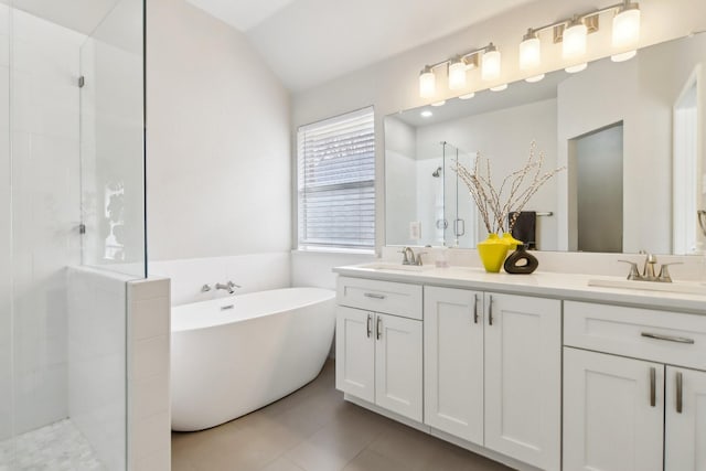 bathroom with double vanity, tiled shower, a sink, and tile patterned floors