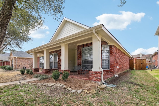 view of front of home with a front yard, a gate, a porch, and brick siding