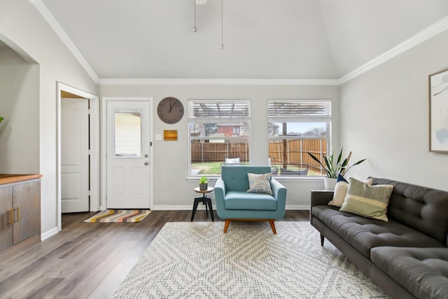 living area with crown molding, baseboards, vaulted ceiling, and wood finished floors