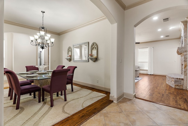 dining room with light tile patterned floors, visible vents, arched walkways, and crown molding