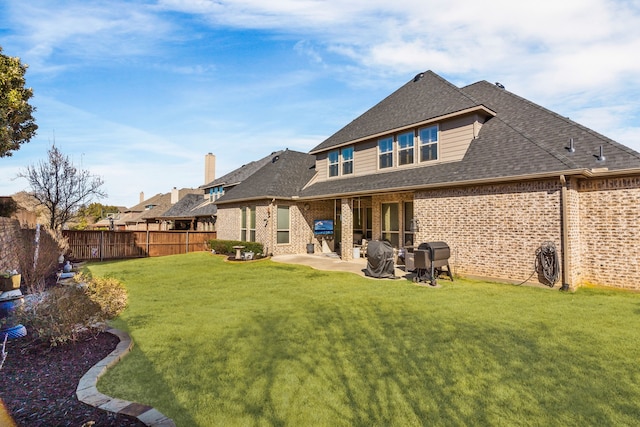 back of house featuring a lawn, a patio, a fenced backyard, roof with shingles, and brick siding