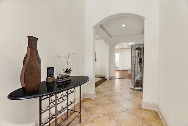 hallway with arched walkways, light tile patterned flooring, baseboards, and crown molding