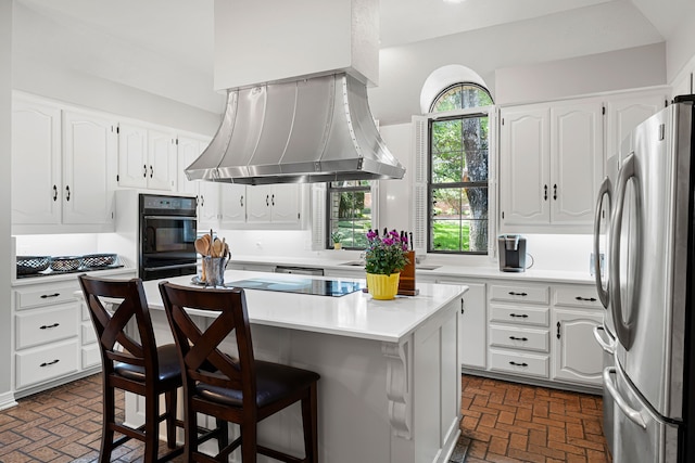 kitchen featuring black appliances, a kitchen bar, light countertops, and white cabinets