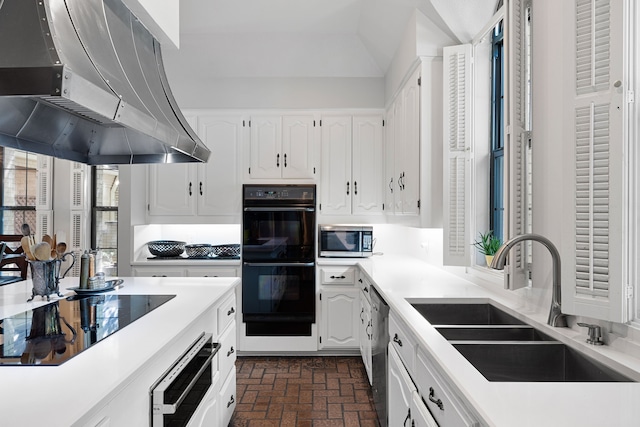 kitchen featuring light countertops, black appliances, white cabinetry, a sink, and exhaust hood