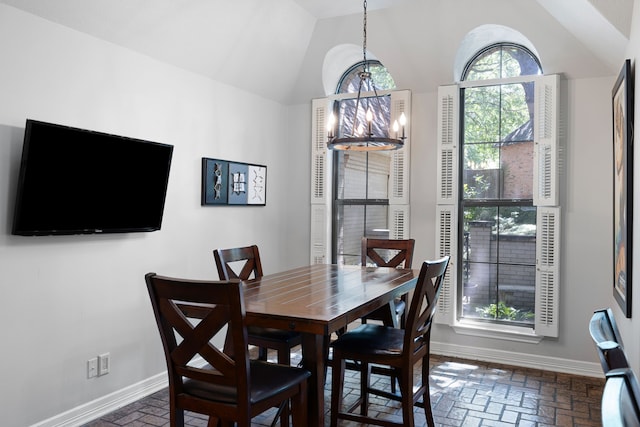 dining area featuring brick floor, a chandelier, and baseboards