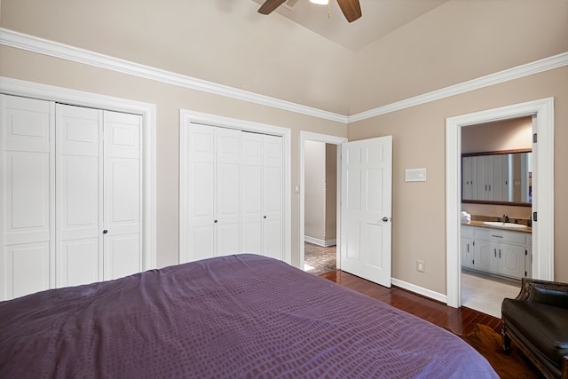 unfurnished bedroom featuring baseboards, ensuite bath, dark wood-style flooring, two closets, and a sink