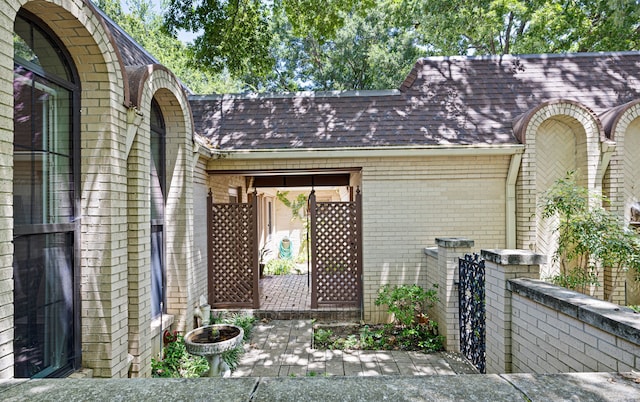 property entrance with brick siding and roof with shingles