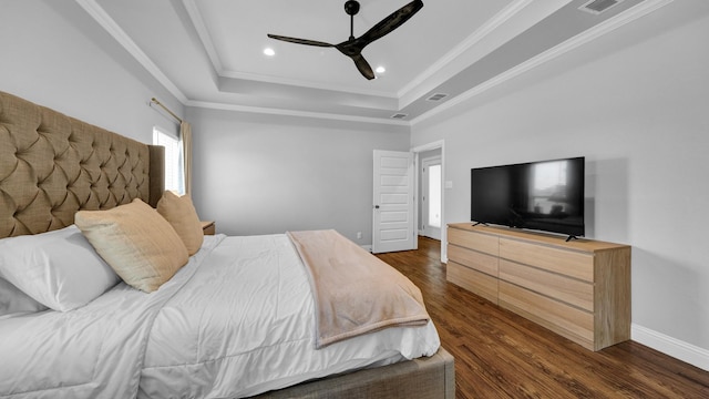 bedroom with a tray ceiling, dark wood-style flooring, crown molding, recessed lighting, and baseboards