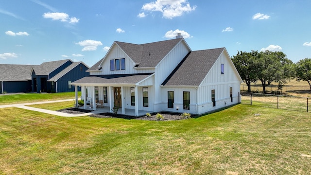 exterior space with a porch, a shingled roof, board and batten siding, fence, and a front lawn