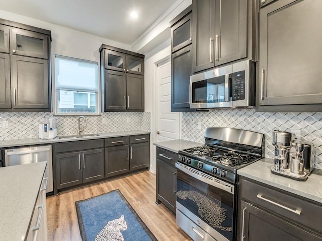 kitchen featuring a sink, glass insert cabinets, stainless steel appliances, and light countertops