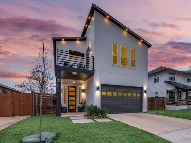 contemporary home featuring a lawn, a garage, fence, a balcony, and concrete driveway