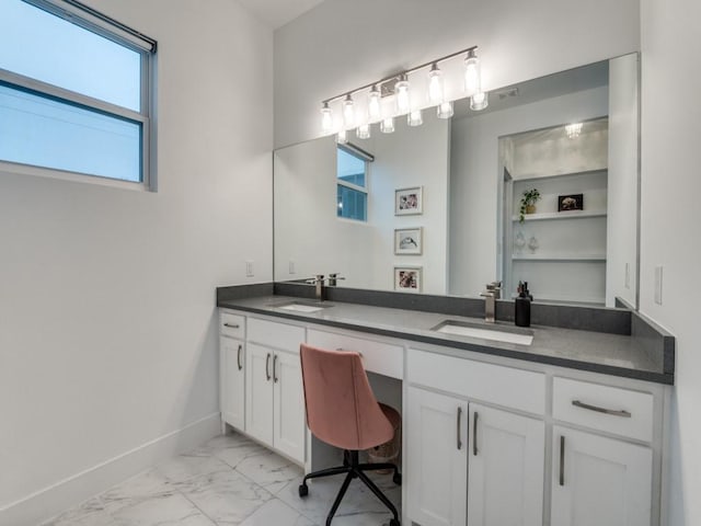 bathroom with marble finish floor, double vanity, a sink, and baseboards