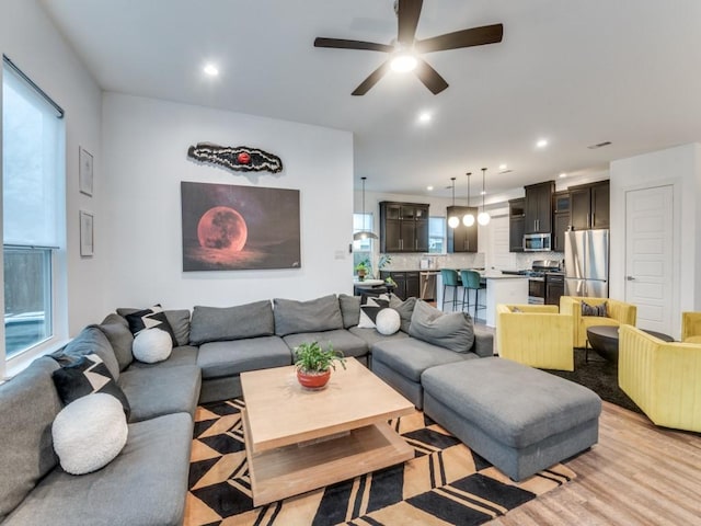 living area featuring light wood-style flooring, ceiling fan, and recessed lighting