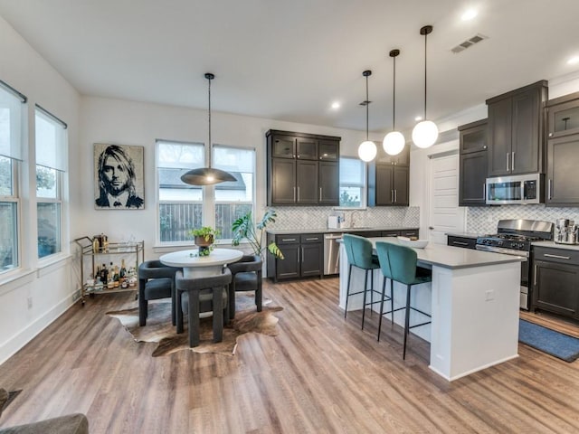 kitchen featuring a center island, decorative light fixtures, visible vents, light countertops, and appliances with stainless steel finishes