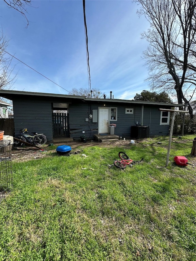 back of property featuring entry steps, central AC, and a yard