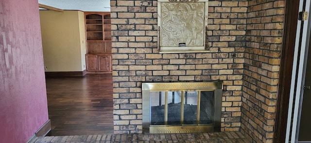 details featuring built in shelves, a brick fireplace, wood finished floors, and baseboards