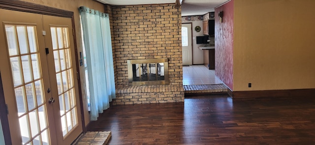 unfurnished living room with a fireplace, dark wood-style flooring, and french doors