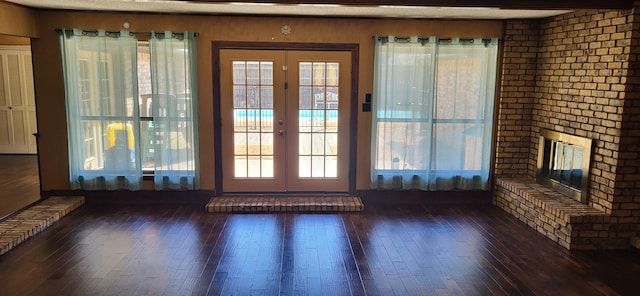 doorway with french doors, dark wood-style flooring, and a fireplace