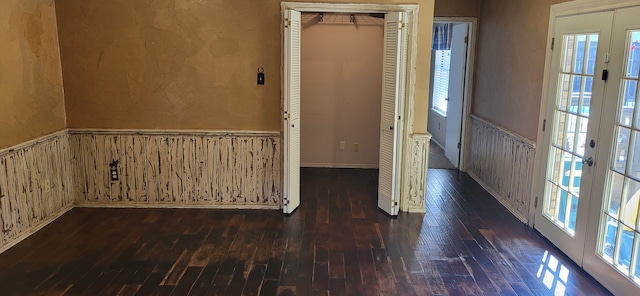 unfurnished room with french doors, dark wood-style flooring, wainscoting, and wood walls