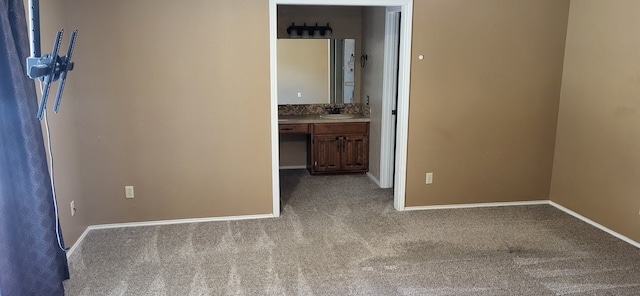 unfurnished bedroom featuring light colored carpet, built in desk, and baseboards