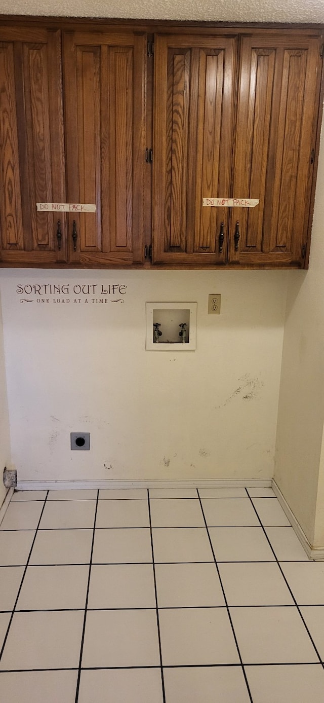 washroom with cabinet space, tile patterned floors, a textured ceiling, hookup for an electric dryer, and washer hookup