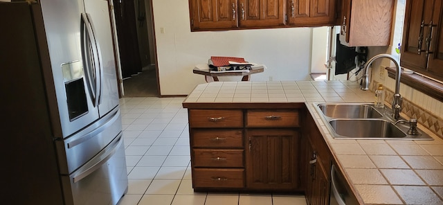 kitchen featuring light tile patterned floors, tile counters, stainless steel appliances, and a sink