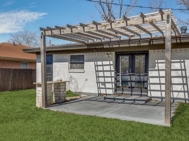 rear view of property with french doors, brick siding, a patio, and a lawn