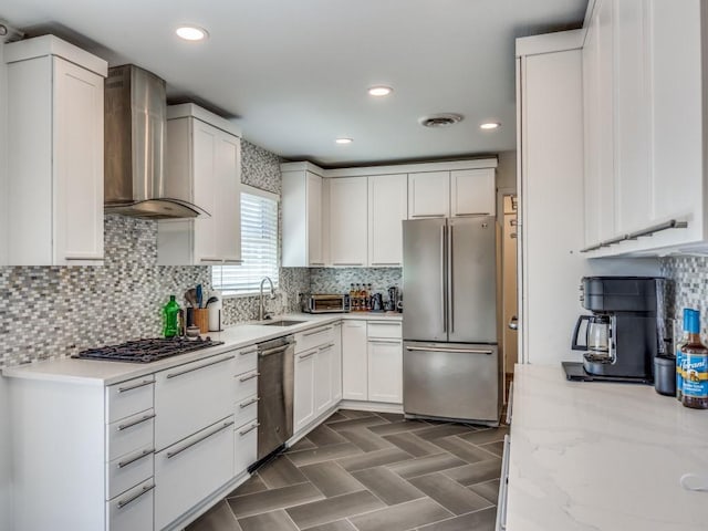 kitchen featuring visible vents, white cabinetry, appliances with stainless steel finishes, wall chimney range hood, and light stone countertops
