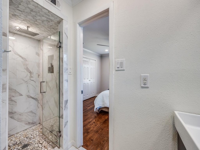 bathroom featuring a marble finish shower, a textured wall, ornamental molding, ensuite bath, and wood finished floors