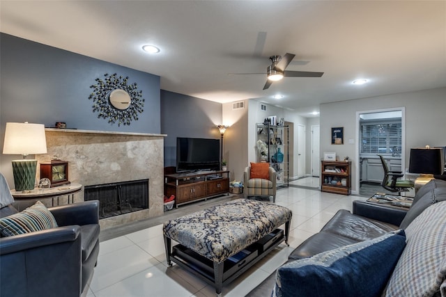 living room with tile patterned flooring, visible vents, a ceiling fan, and a high end fireplace