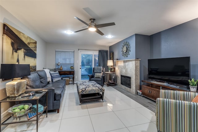 living room with a premium fireplace, a ceiling fan, and light tile patterned flooring