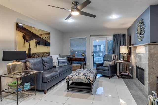 living room featuring a ceiling fan, a fireplace, and light tile patterned floors