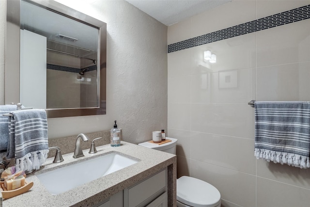 bathroom featuring toilet, vanity, visible vents, and a textured wall