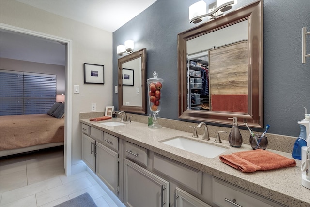 ensuite bathroom featuring tile patterned floors, a sink, ensuite bath, and double vanity